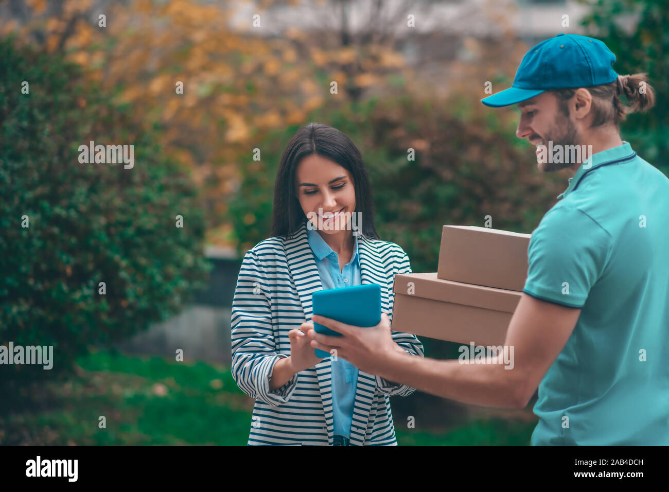 Delivery man holding tablet while standing near client Stock Photo