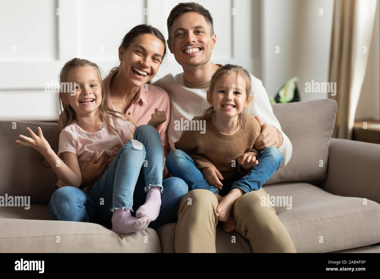 Happy parents and funny children daughters bonding looking at camera Stock Photo