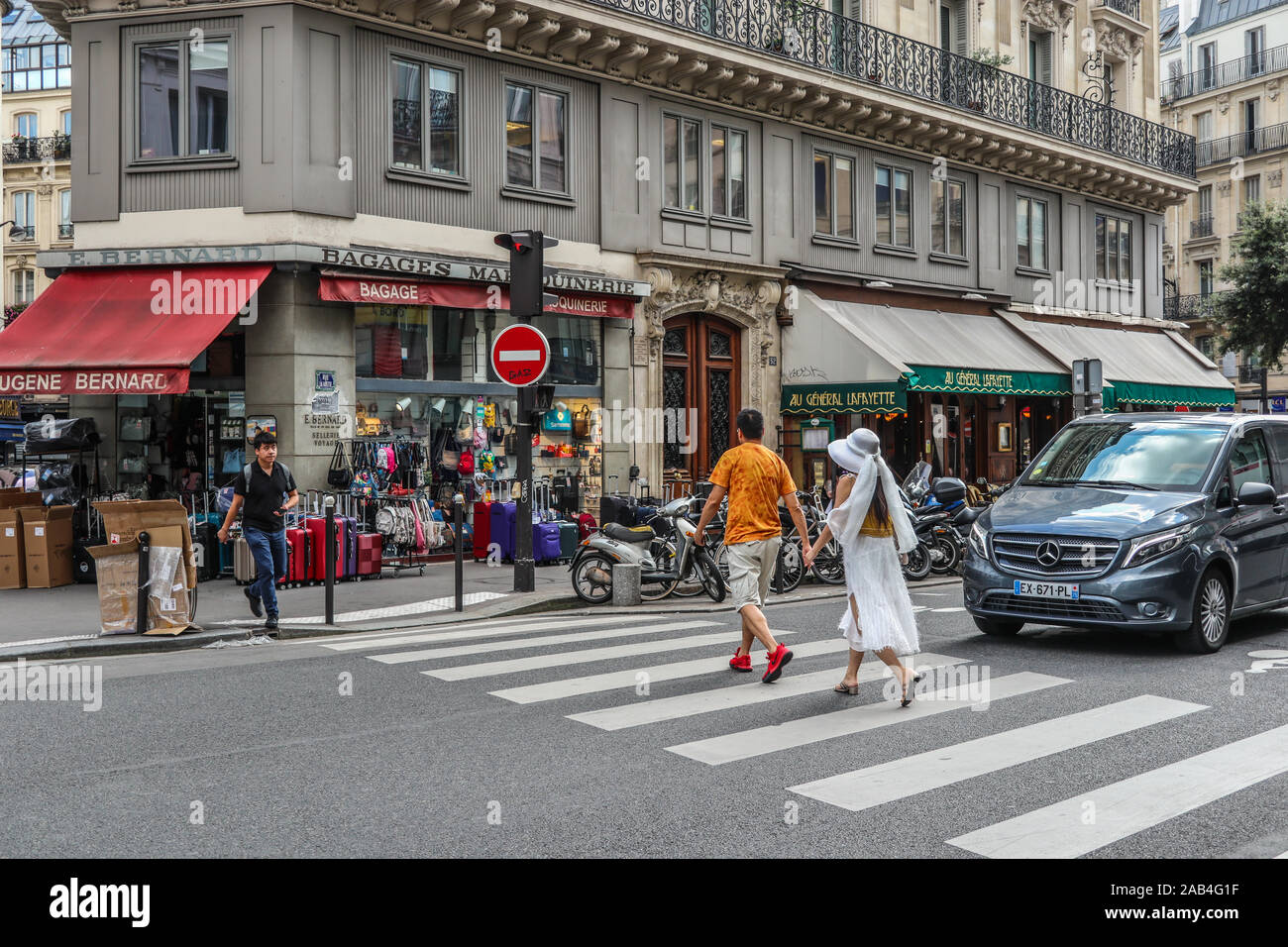 Couple hold hands as the cross road at a zebra crossing in Paris