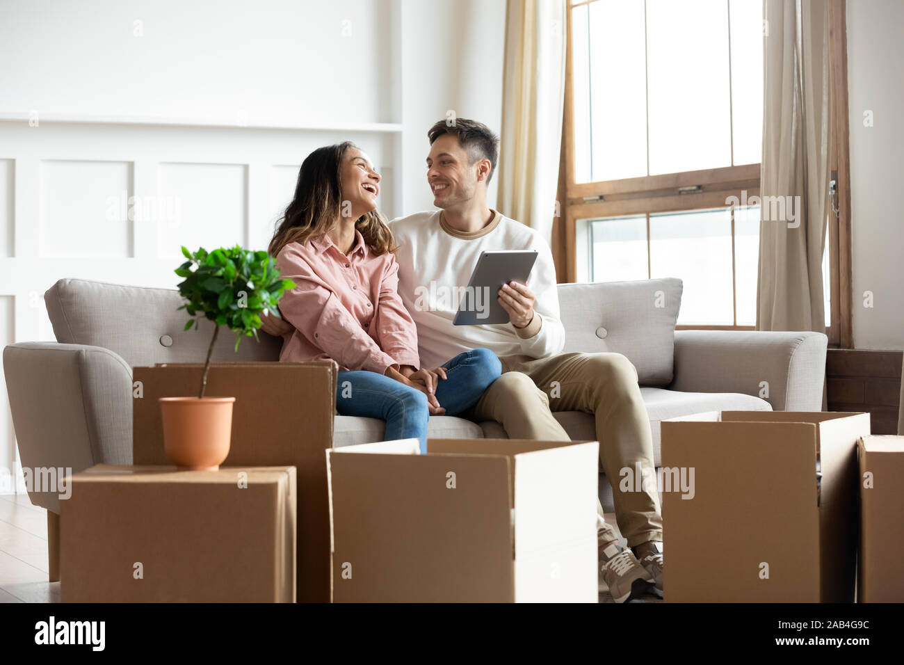Smiling couple talking using tablet computer on moving relocation day Stock Photo
