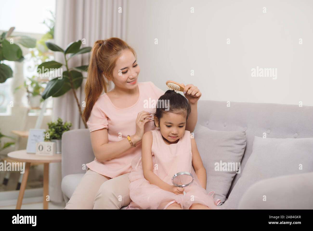 A young mother combing a hair little girl Stock Photo