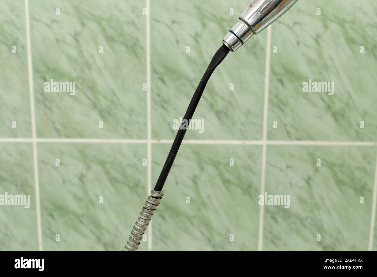 Old damaged leaking shower hose in the bathroom of house Stock Photo