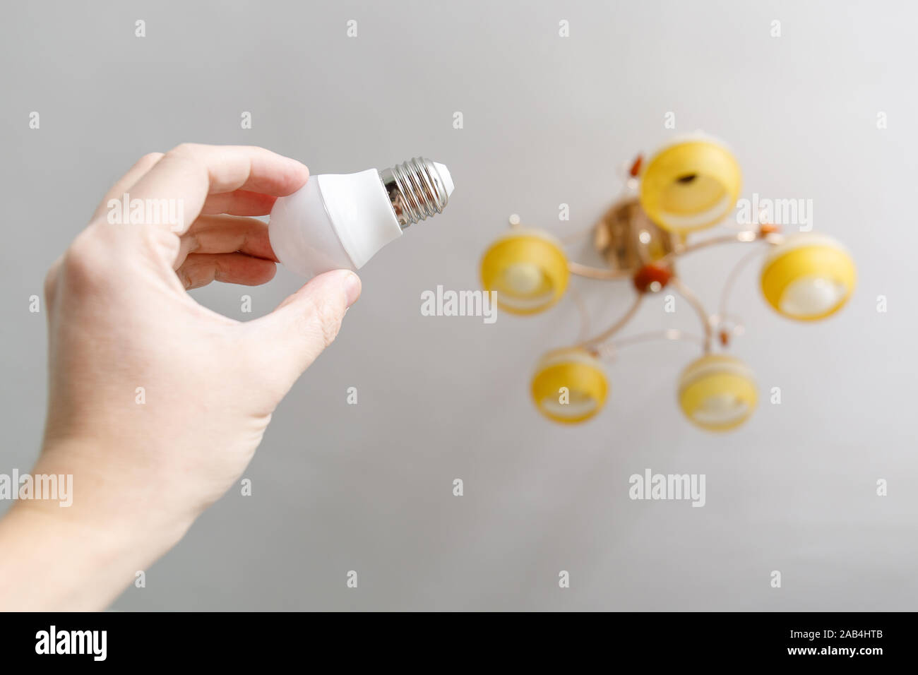 Hand Of Man Screwing New Lightbulb Into Ceiling Lamp Stock Photo