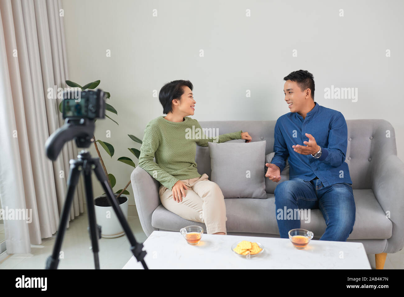 Young couple video bloggers streaming live video using camera on tripod. Stock Photo