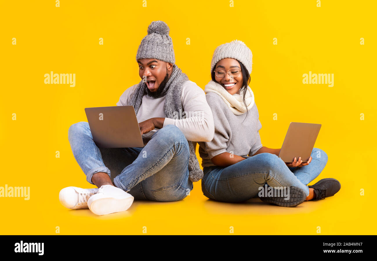 WInter guy and girl betting online, using laptop Stock Photo
