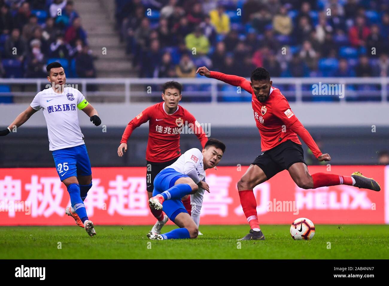Brazilian-born Portuguese football player Dyego Sousa of Shenzhen F.C., right, shoots during the 28th round match of Chinese Football Association Super League (CSL) against Tianjin TEDA in Tianjin, China, 23 November 2019. Tianjin TEDA slashed Shenzhen F.C. with 3-0. Stock Photo