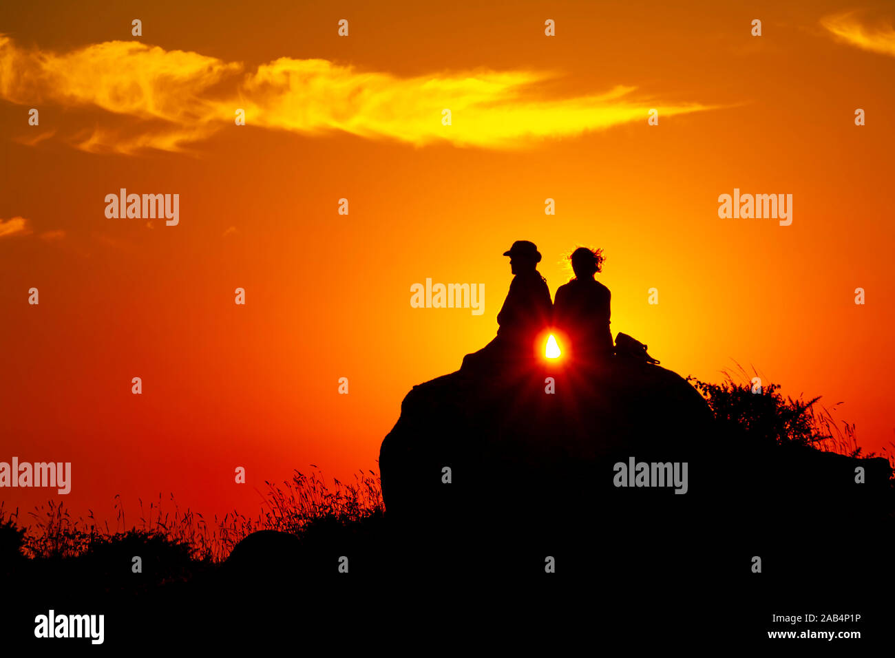 Silhouette of a romance couple looking at the sunset on an orange sky ...