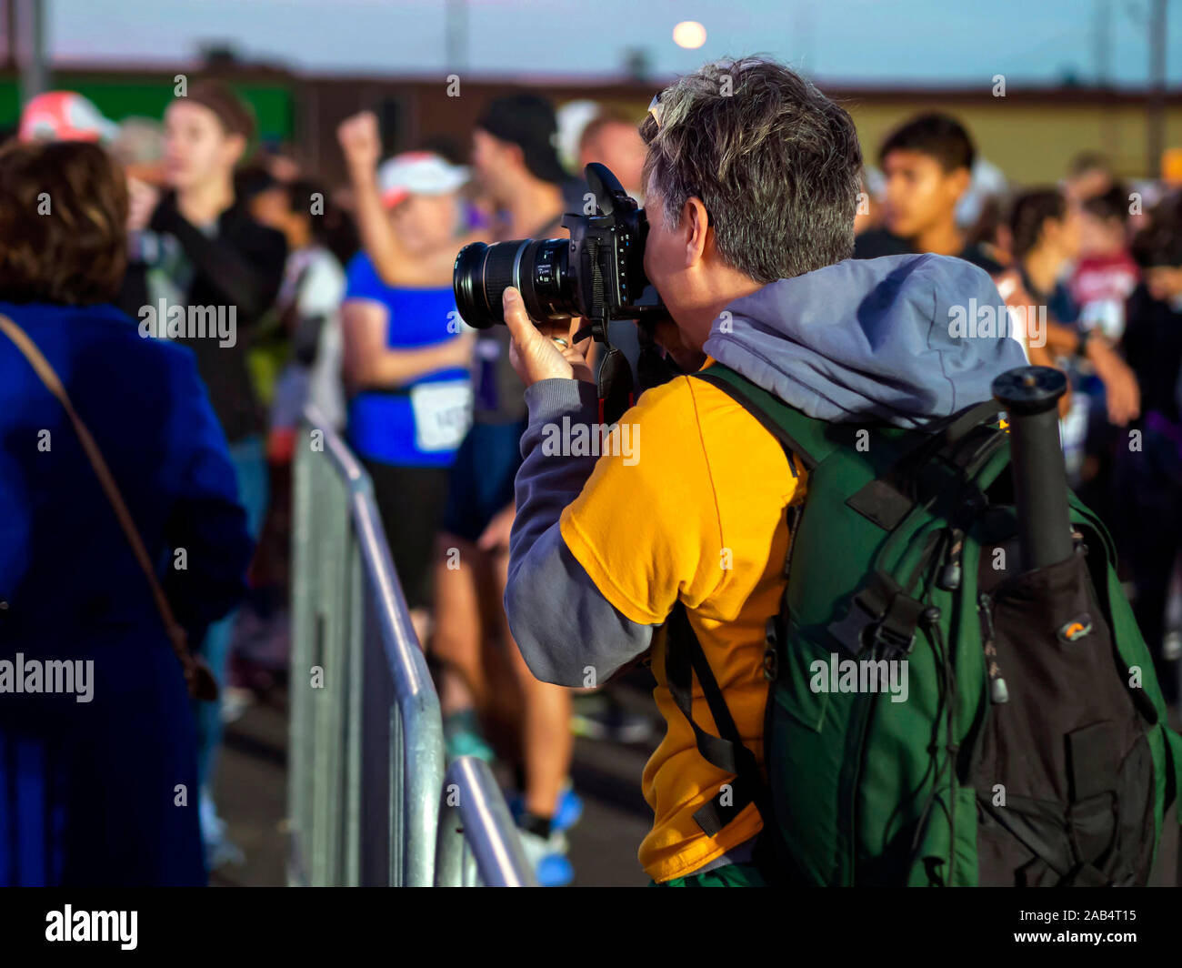 Female photographer focuses her camera on the crowd of competitors awaiting the start of the Corpus Christi 15th annual Harbor Half Marathon. Stock Photo