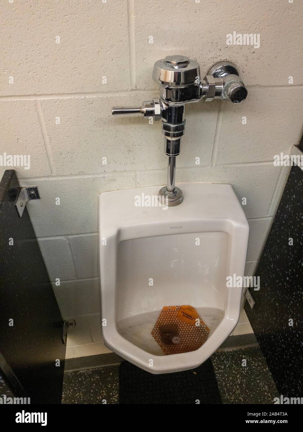 Closeup on clogged urinal on the wall of mens toilet, filled with