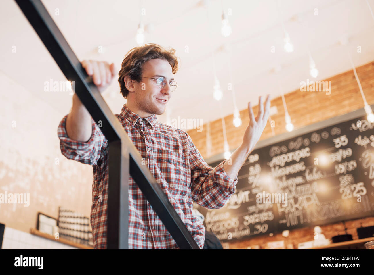 Thoughtful young man is sitting in confectionery shop. She is drinking coffee while waiting for someone Stock Photo