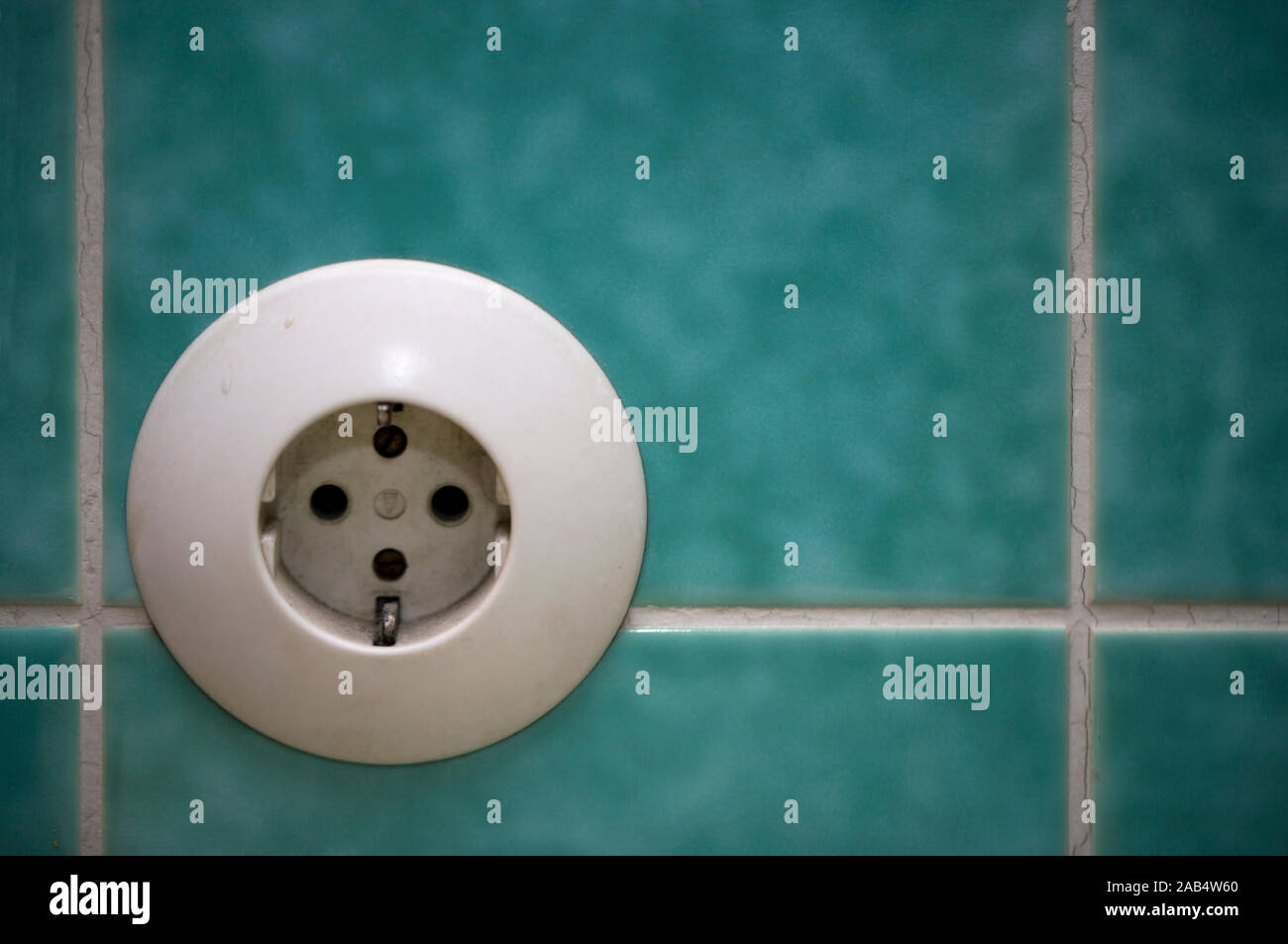 Old electrical socket on tiles in a bathroom Stock Photo