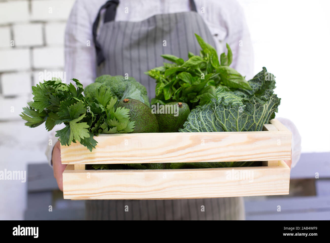 Female farmer holding eco wooden box with green grocery Stock Photo - Alamy