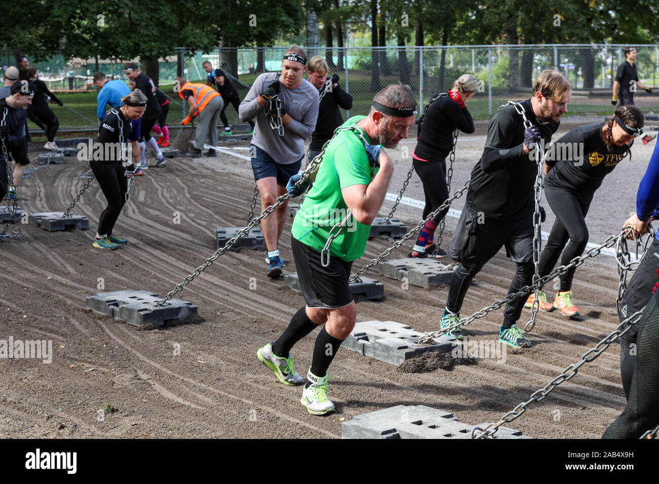 Though Viking obstacle course race 2019 participants pulling heavy concrete blocks on chain in Helsinki, Finland Stock Photo