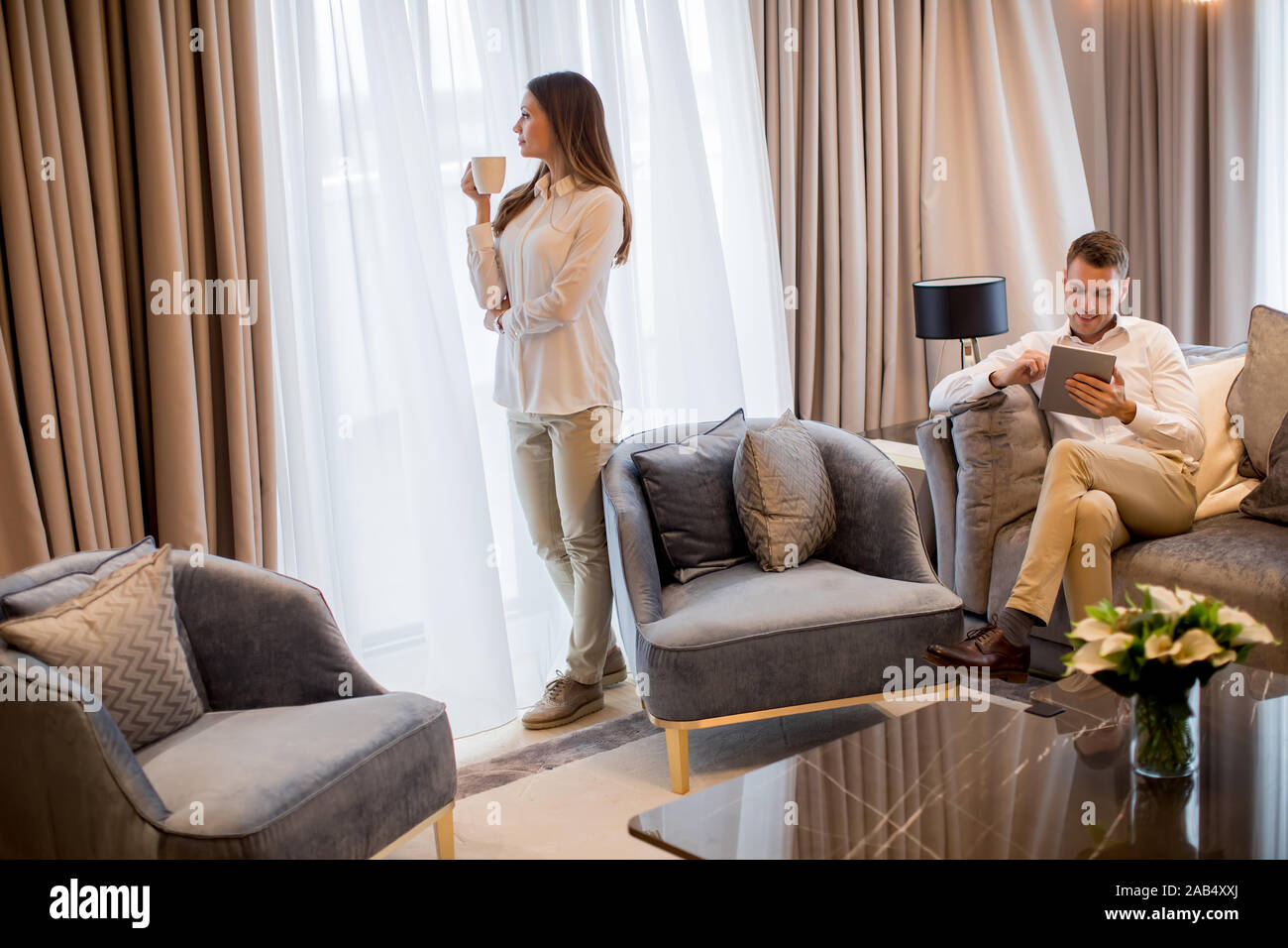 Young couple drinking coffee and using digital tablet in the luxury contemporary apartment Stock Photo