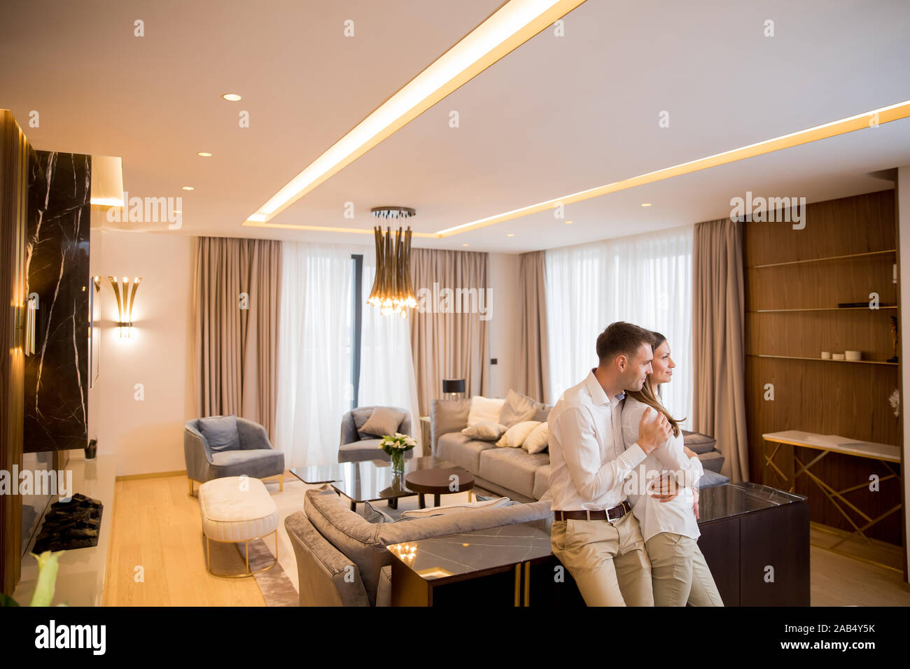 Young couple embracing standing in living room of a contemporary apartment Stock Photo
