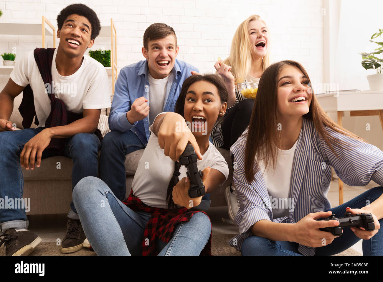 Playful friends playing video games online and having fun Stock