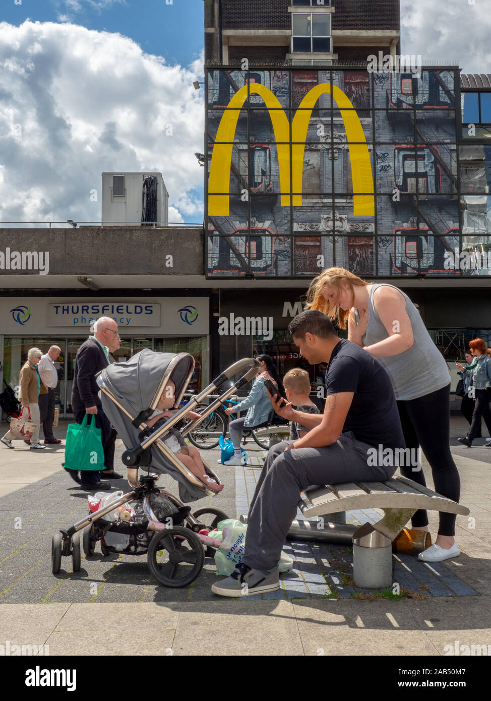 A father and child in a pushchair sat outside a town centre McDonalds. Stock Photo