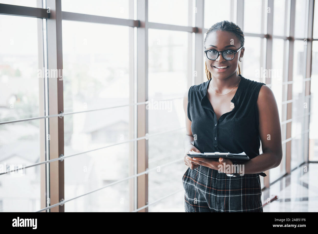 A thoughtful African American business woman wearing glasses holding documents Stock Photo