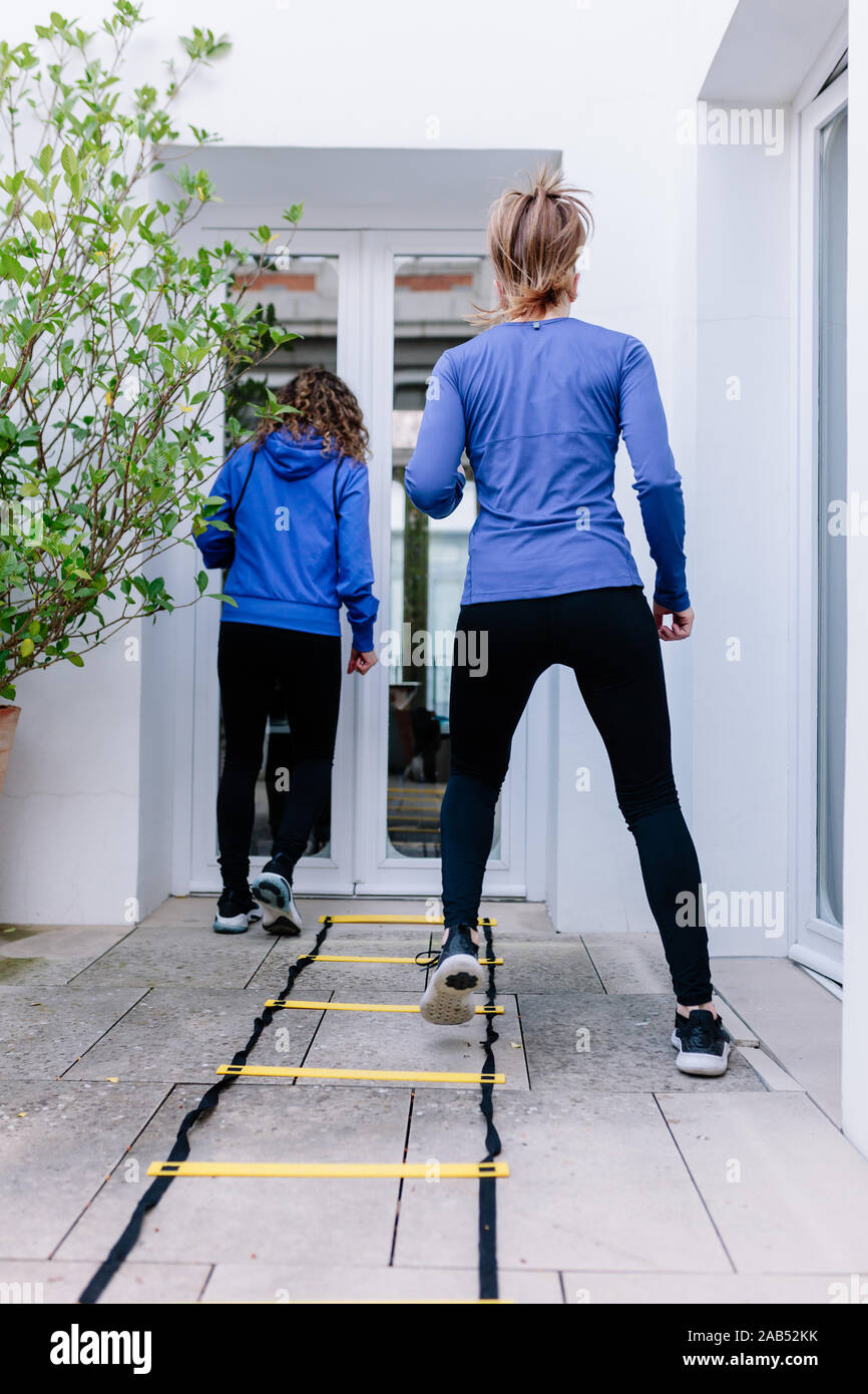 Two young women doing agility ladder exercise on a terrace Stock Photo