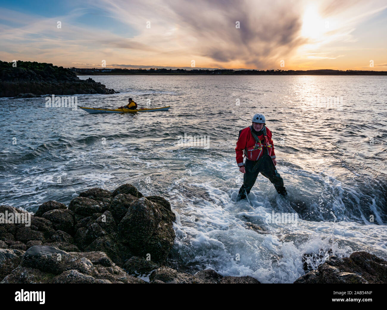 Lothian Sea Kayak Club prepare to leave from rocky shore with kayaks at sunset, Lamb Island, Firth of Forth, Scotland, UK Stock Photo