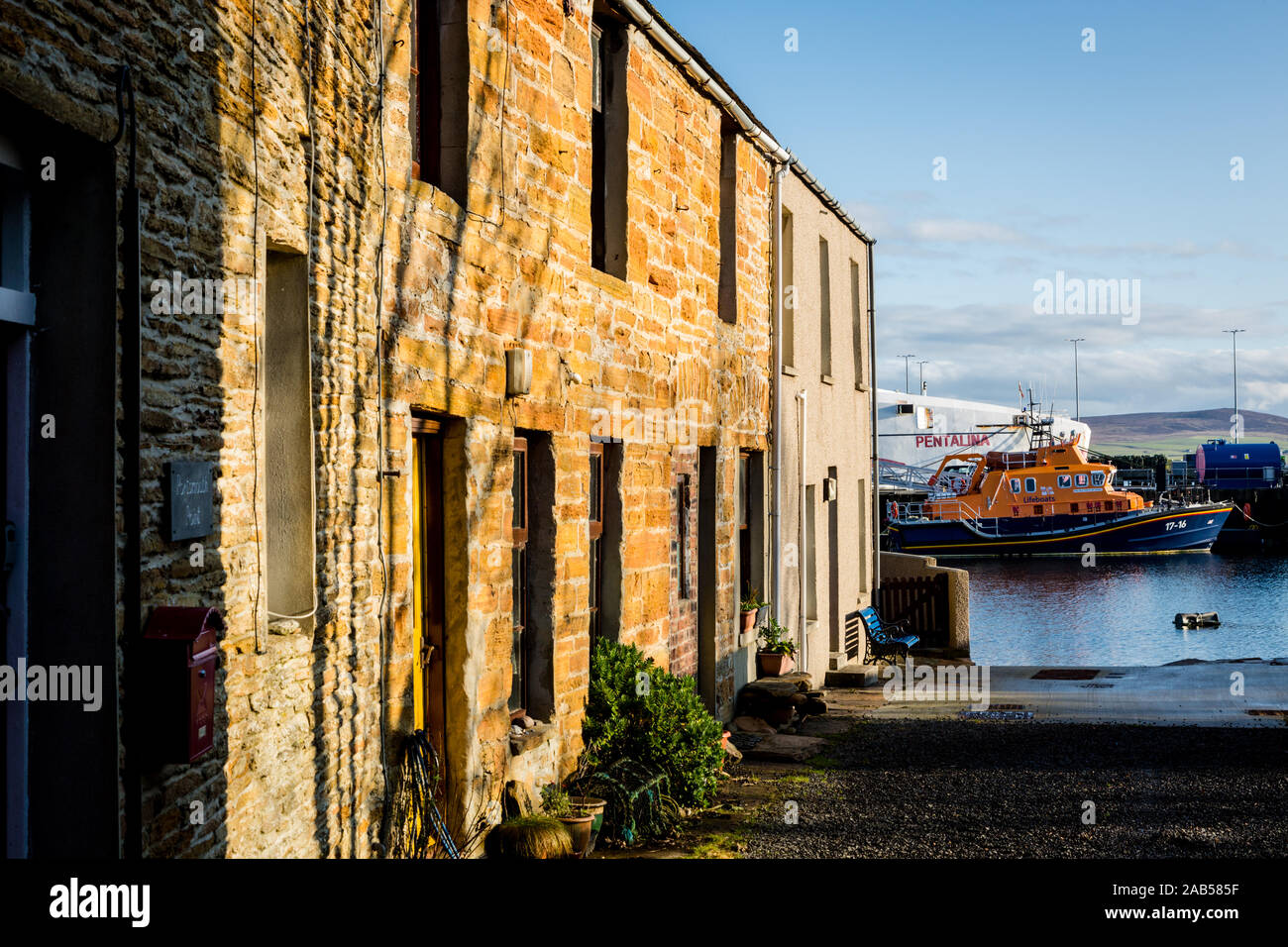 Side street in Stromness, Orkney, with a fery ship and RNLI boat in the water Stock Photo