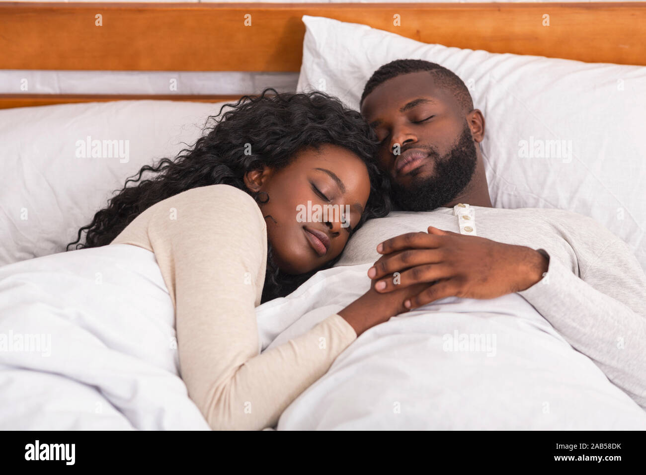 Afro couple sleeping in comfortable bed at home Stock Photo - Alamy