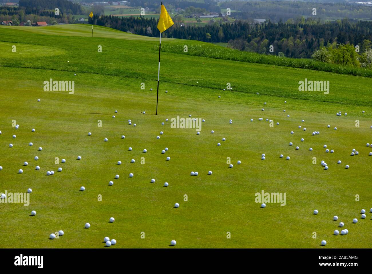 Golf Green with Flag Stick and Many Golf Balls in Switzerland. Stock Photo