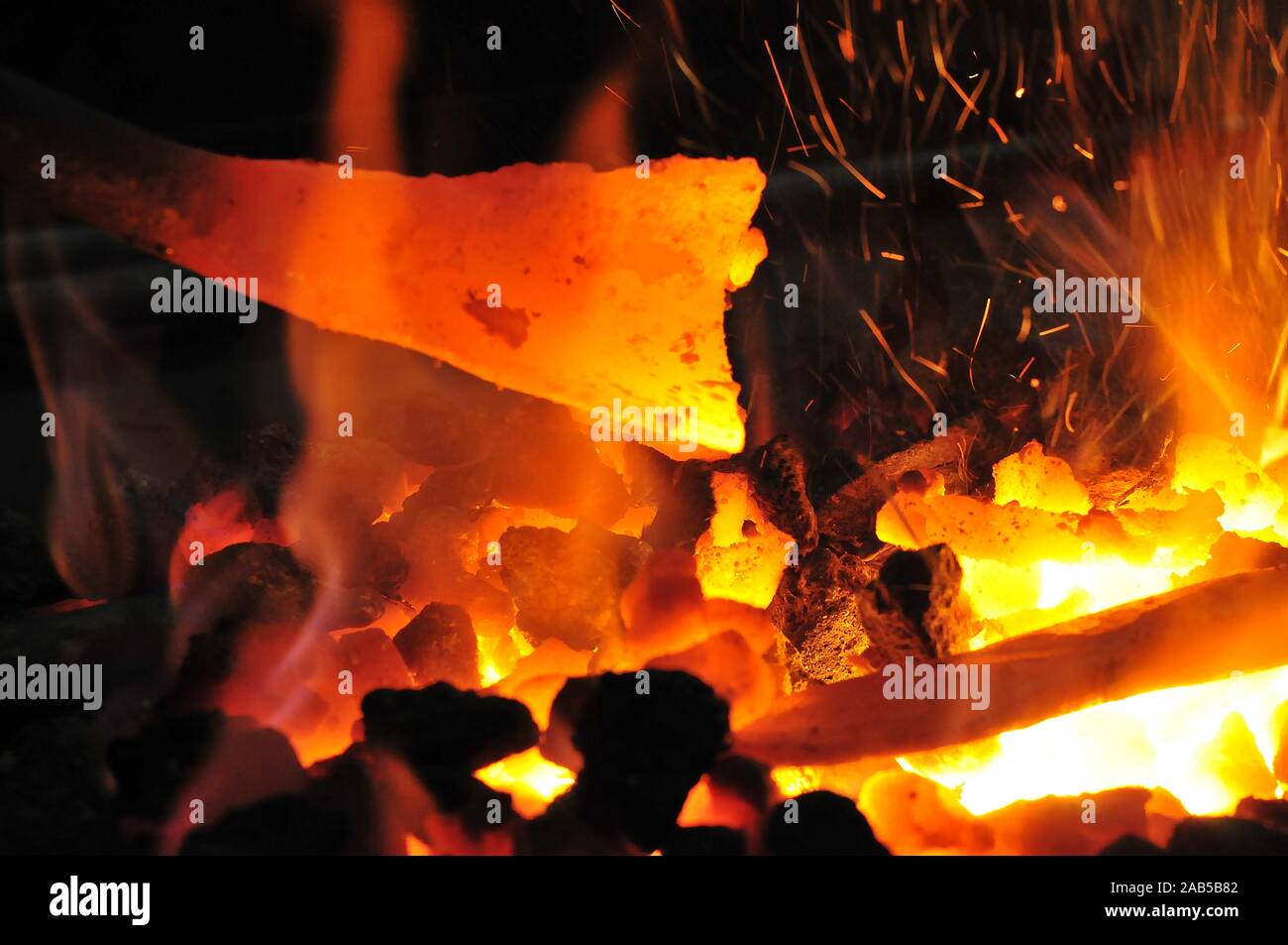 glowing iron in glowing coal in a forge while forging Stock Photo