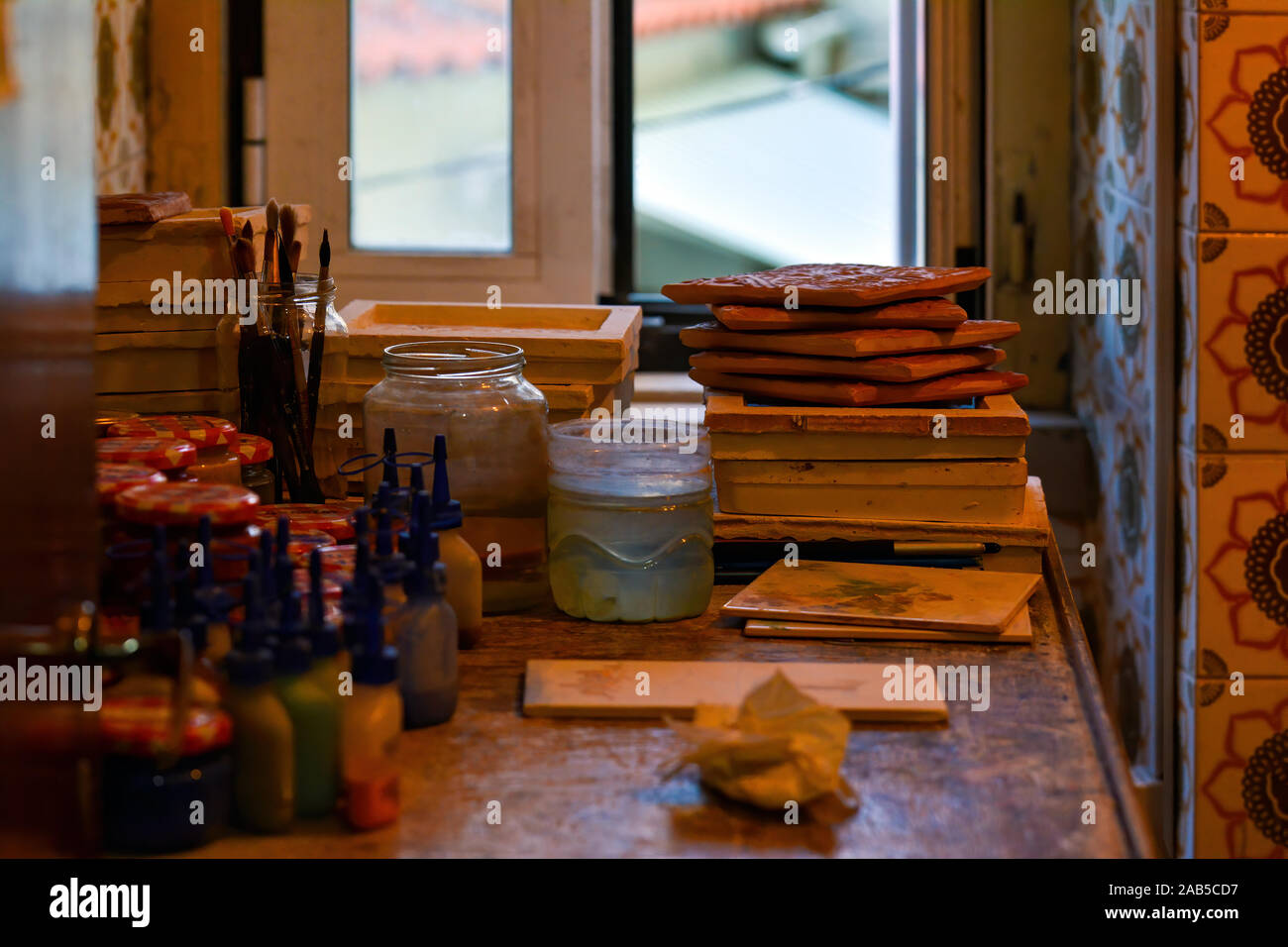 Ceramic tiles, dyes and brushes in a rustic room. Portuguese tradition. Stock Photo