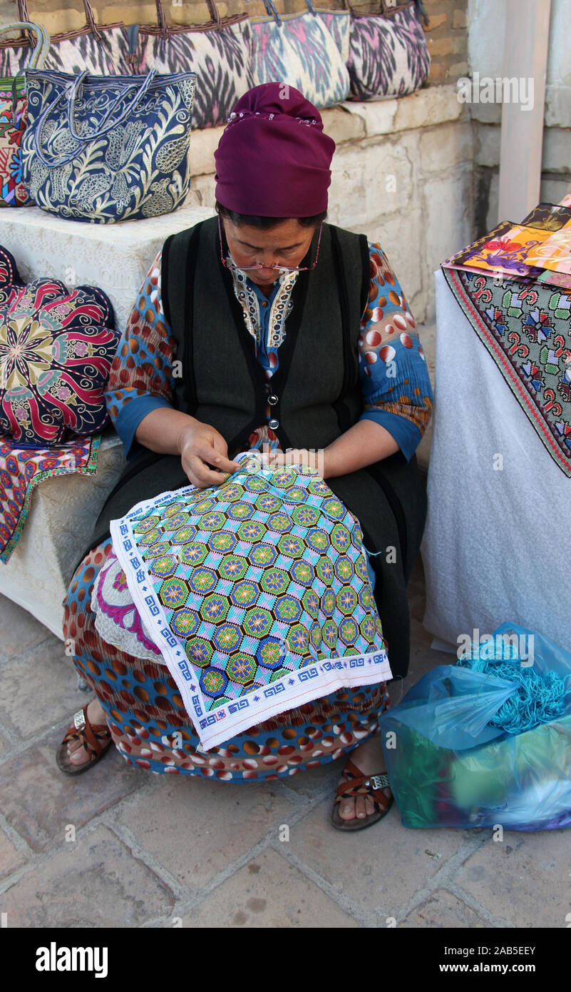 Uzbek woman doing traditional beadwork at her market stall Stock Photo