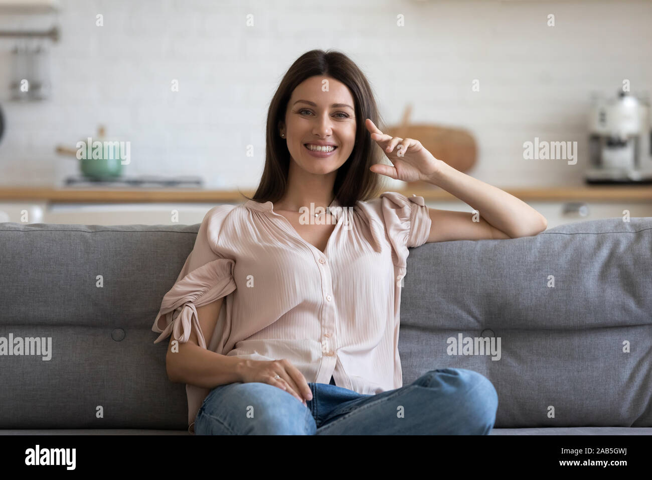 Happy attractive young woman sitting on sofa looking at camera Stock ...