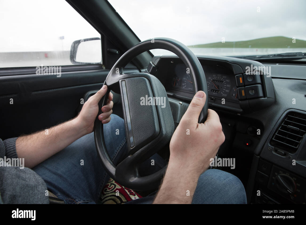 Car Interior. Male arms holding leathern rudder of car .the man grabs ...