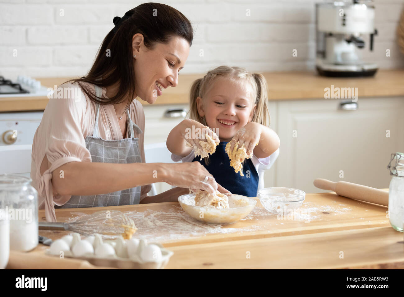 Funny child helper playing with dough helping mom in kitchen Stock Photo