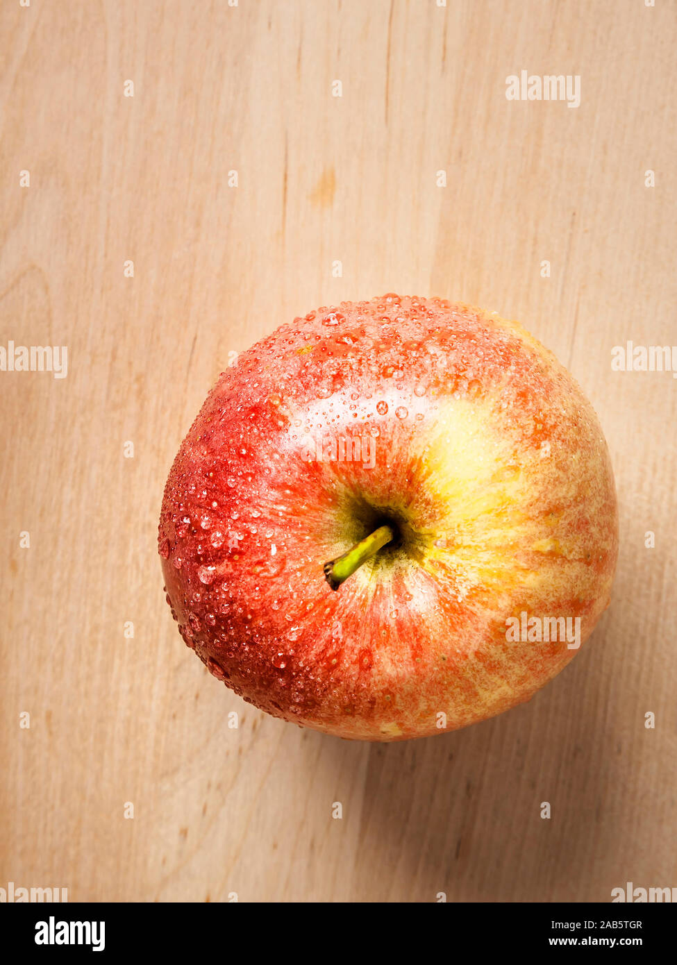 Ein roter Apfel auf hoelzernem Untergrund Stock Photo