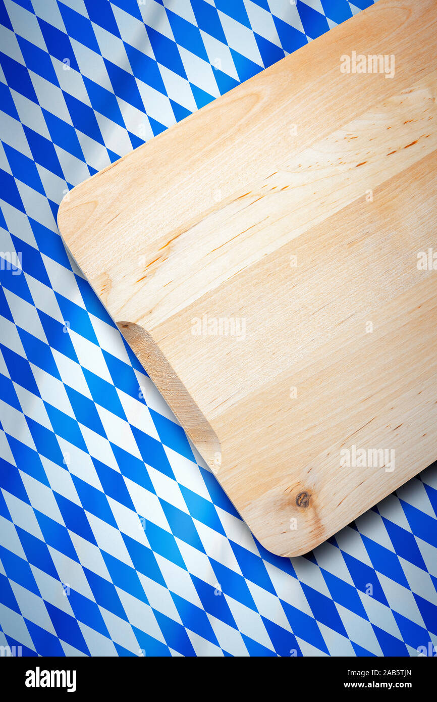 Ein schoenes hoelzernes Brotzeitbrett auf einem Hintergrund mit blauen und weissen Rauten Stock Photo