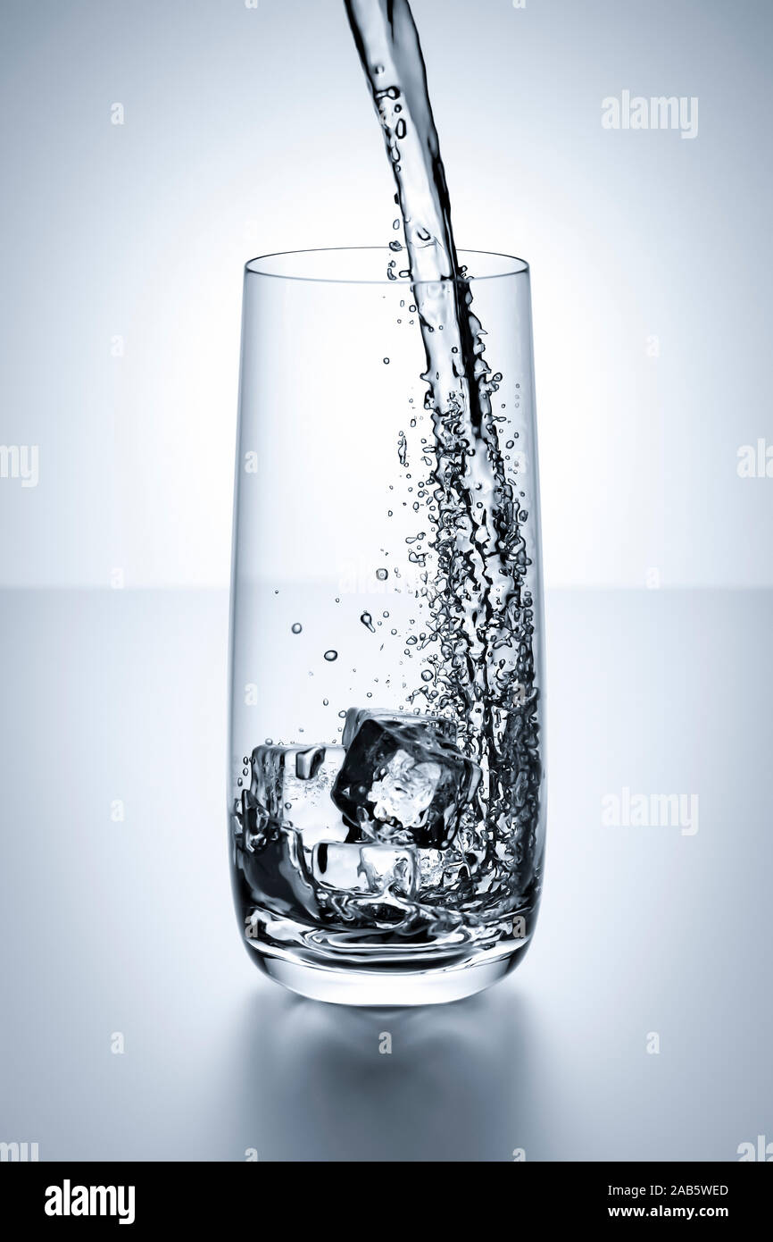 Ein Wasserglas, in das eingeschenkt wird. Stock Photo