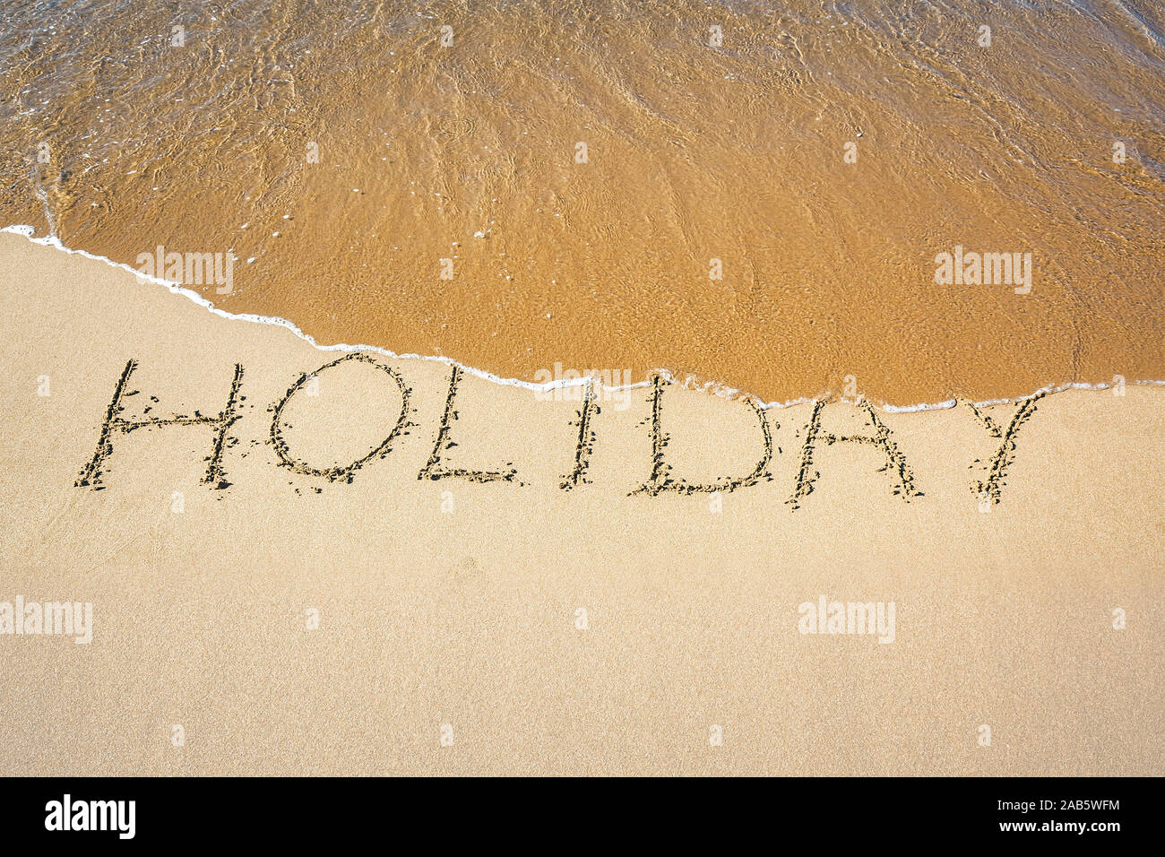 Ein Sandstrand, auf dem 'Holiday' geschrieben steht. Stock Photo