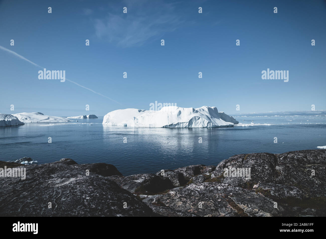 Arctic nature landscape with icebergs in Greenland icefjord with midnight sun sunset sunrise in the horizon. Early morning summer alpenglow during Stock Photo