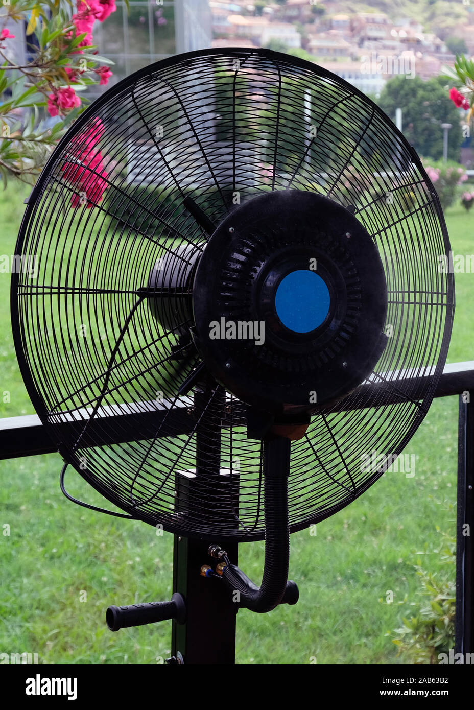 Black fan with humidifier in a cafe on a hot summer day. Special fan with water spray for cooling in the heat. Stock Photo
