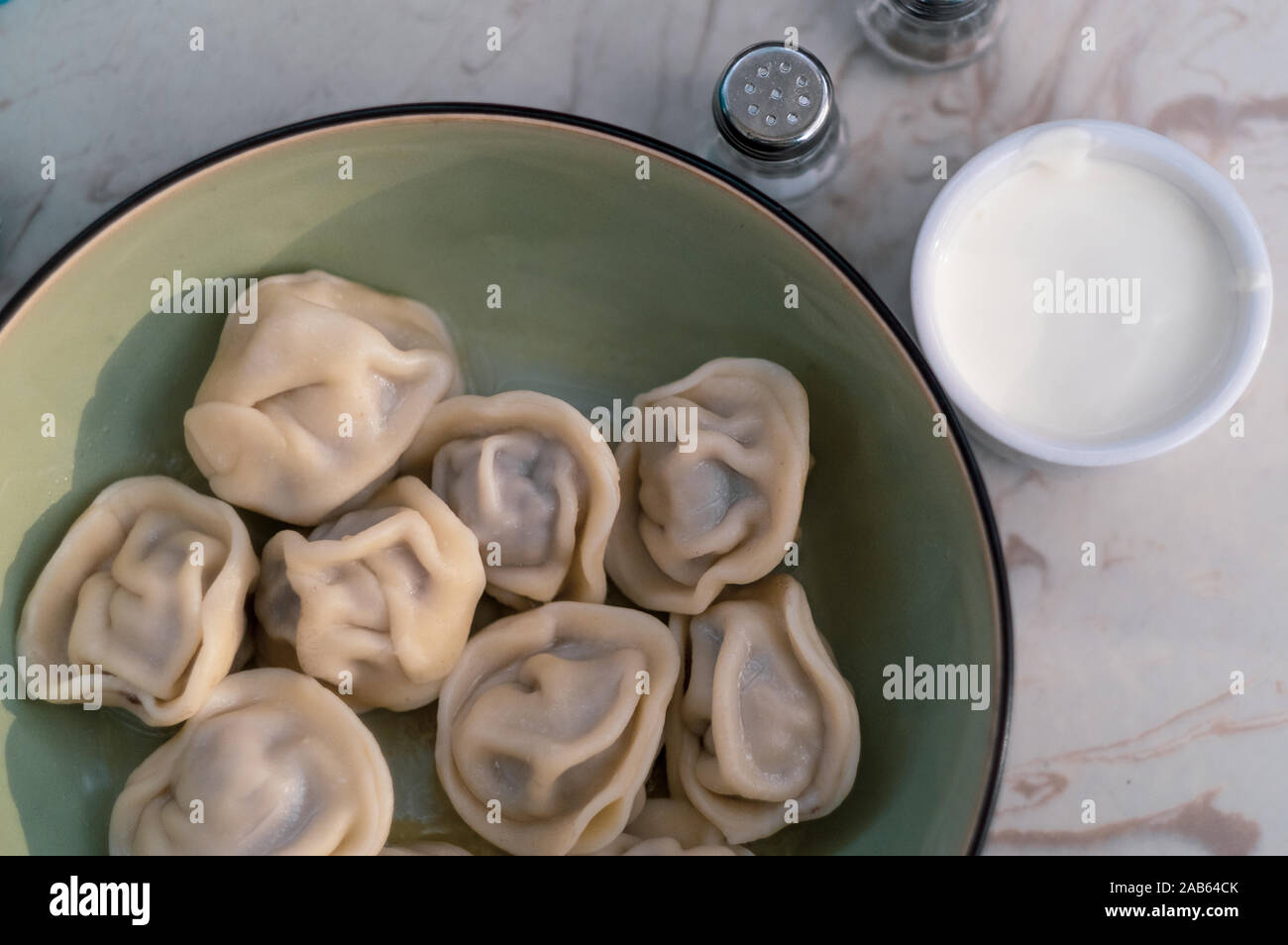 Meat dumplings russian pelmeni with pepper and sour cream in bowl Stock Photo