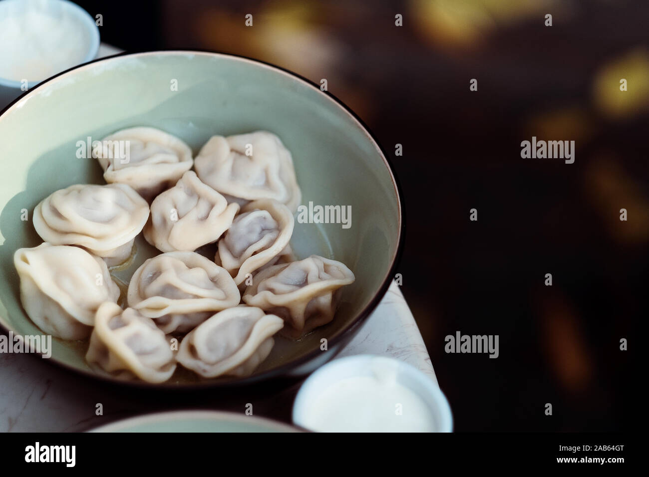 Meat dumplings russian pelmeni with pepper and sour cream in bowl Stock Photo