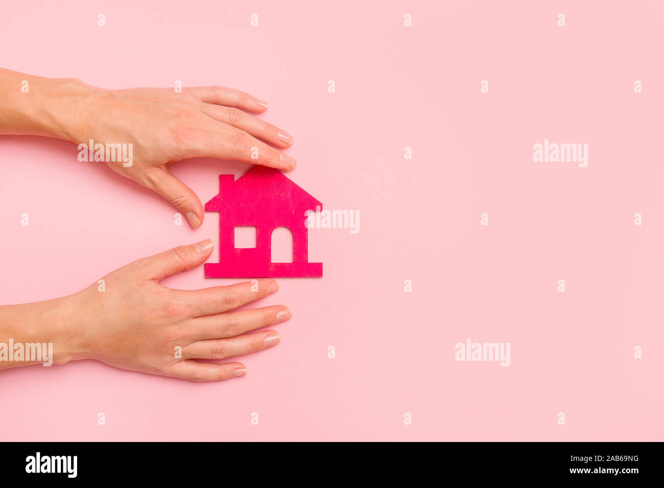 Hand Holding Pink house on pink background. New home concept Stock Photo