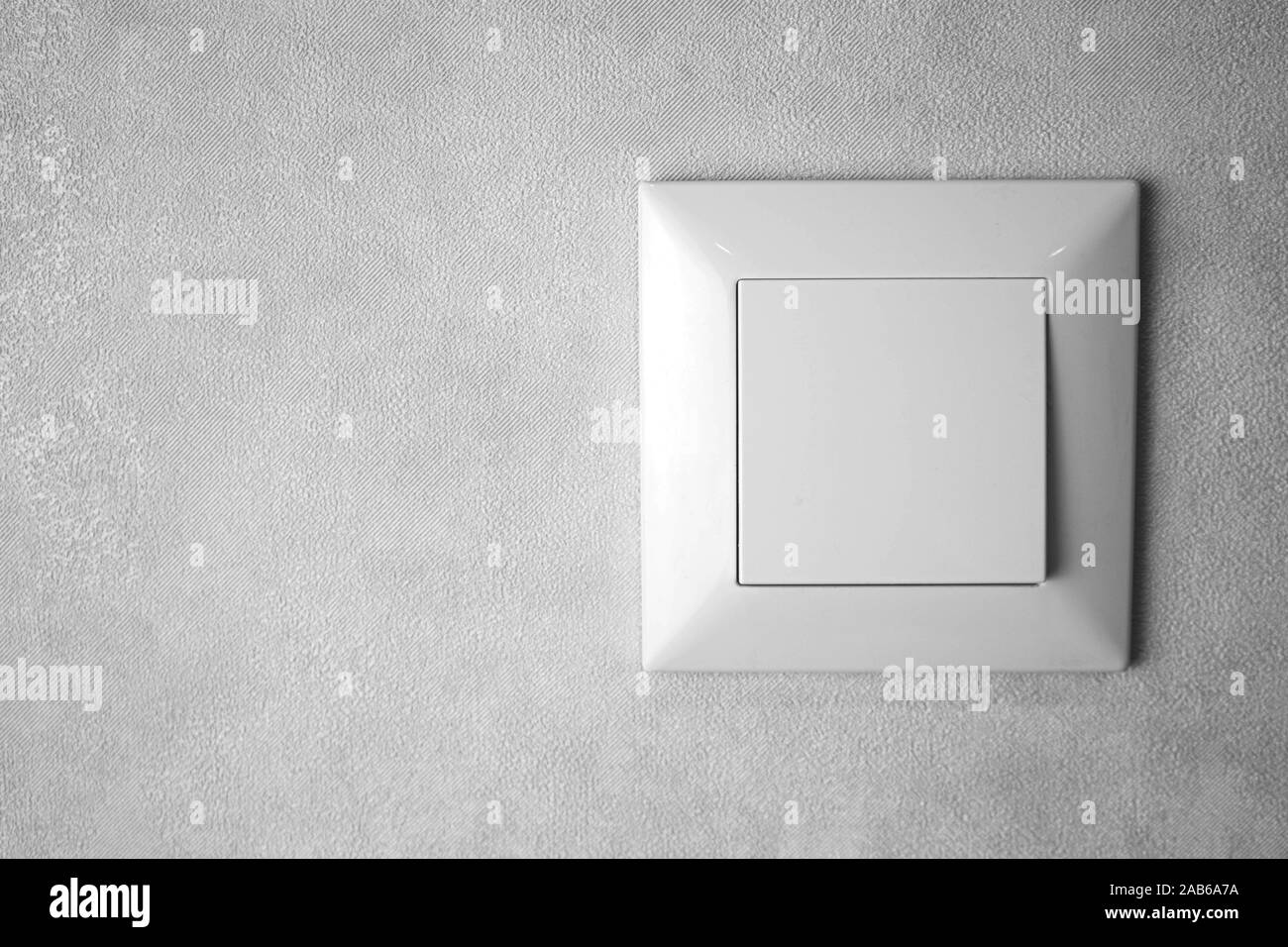 a light switch, a plastic mechanical switch of white color installed on a light gray wall. Stock Photo