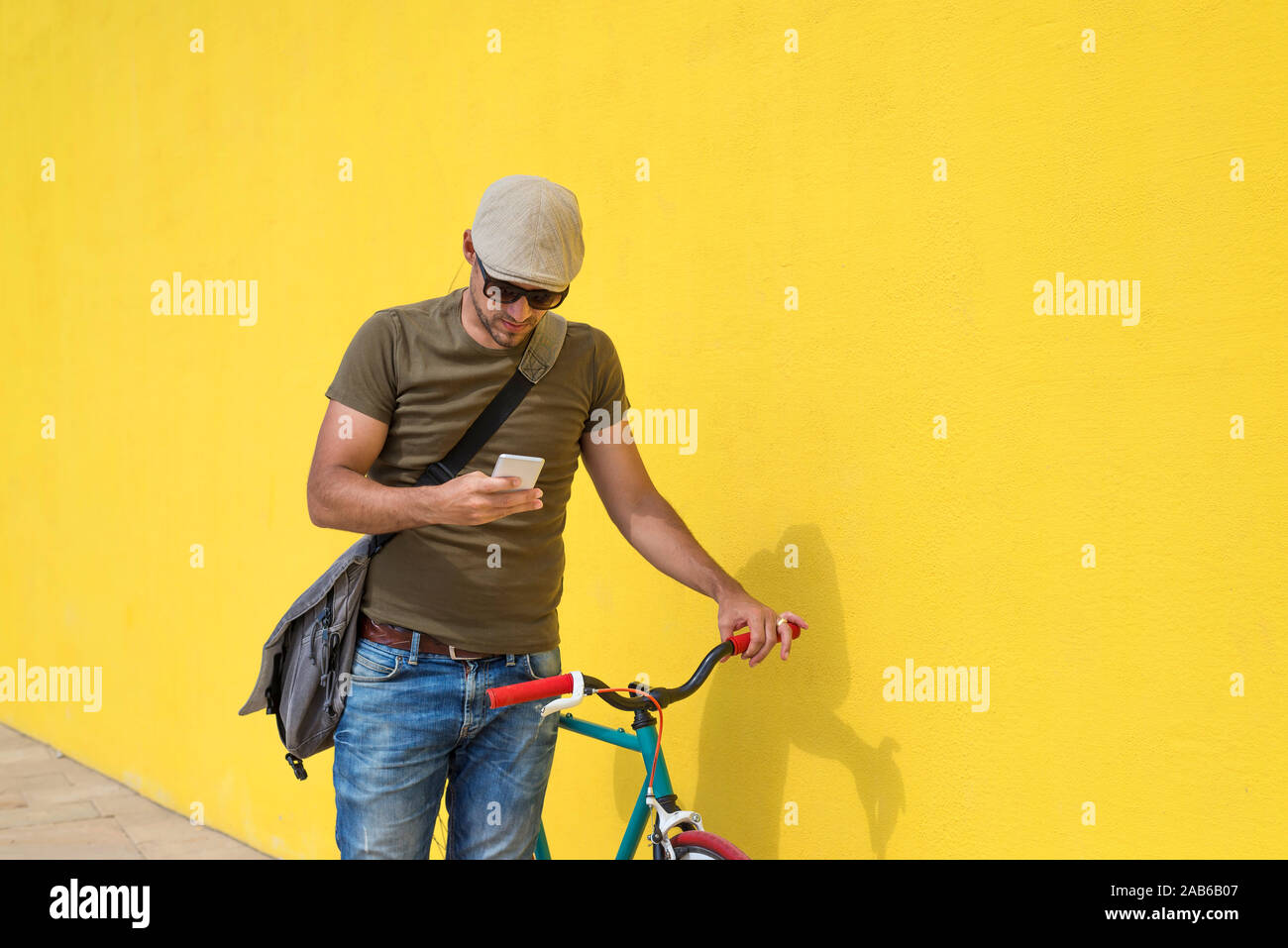 Trendy man using his smartphone outdoors while sitting on a fixed bike Stock Photo