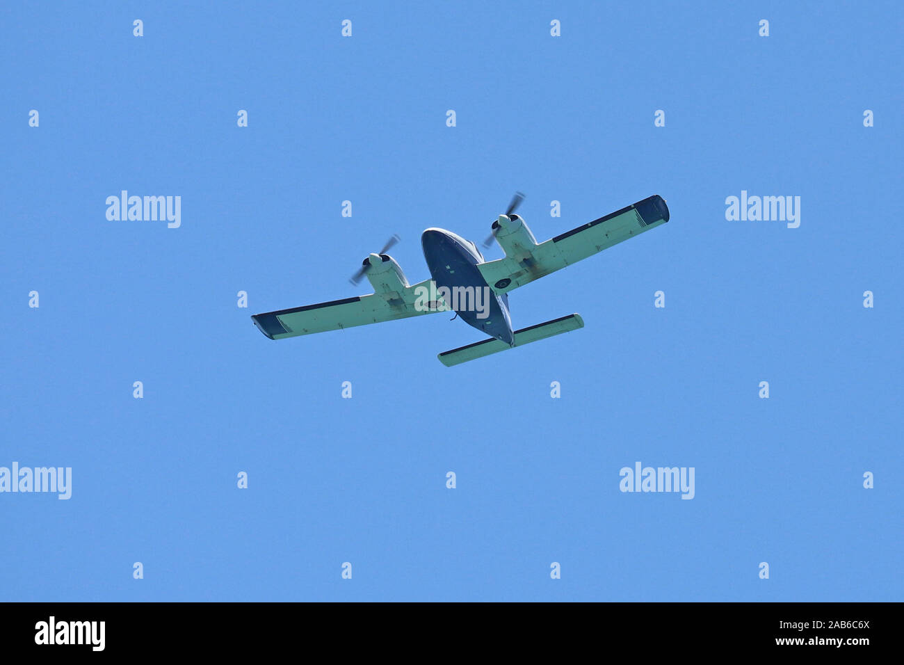 Twin engine light aircraft flying overhead with a blue sky background. Stock Photo