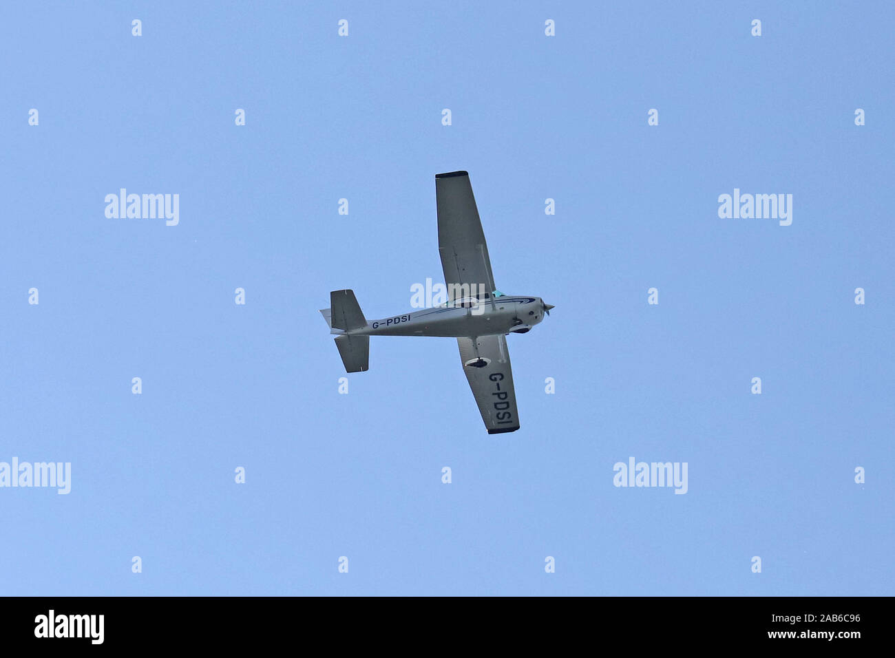 Cessna 172N Skyhawk a single engined light aircraft G-PDSI flying overhead, with a blue sky background. Stock Photo