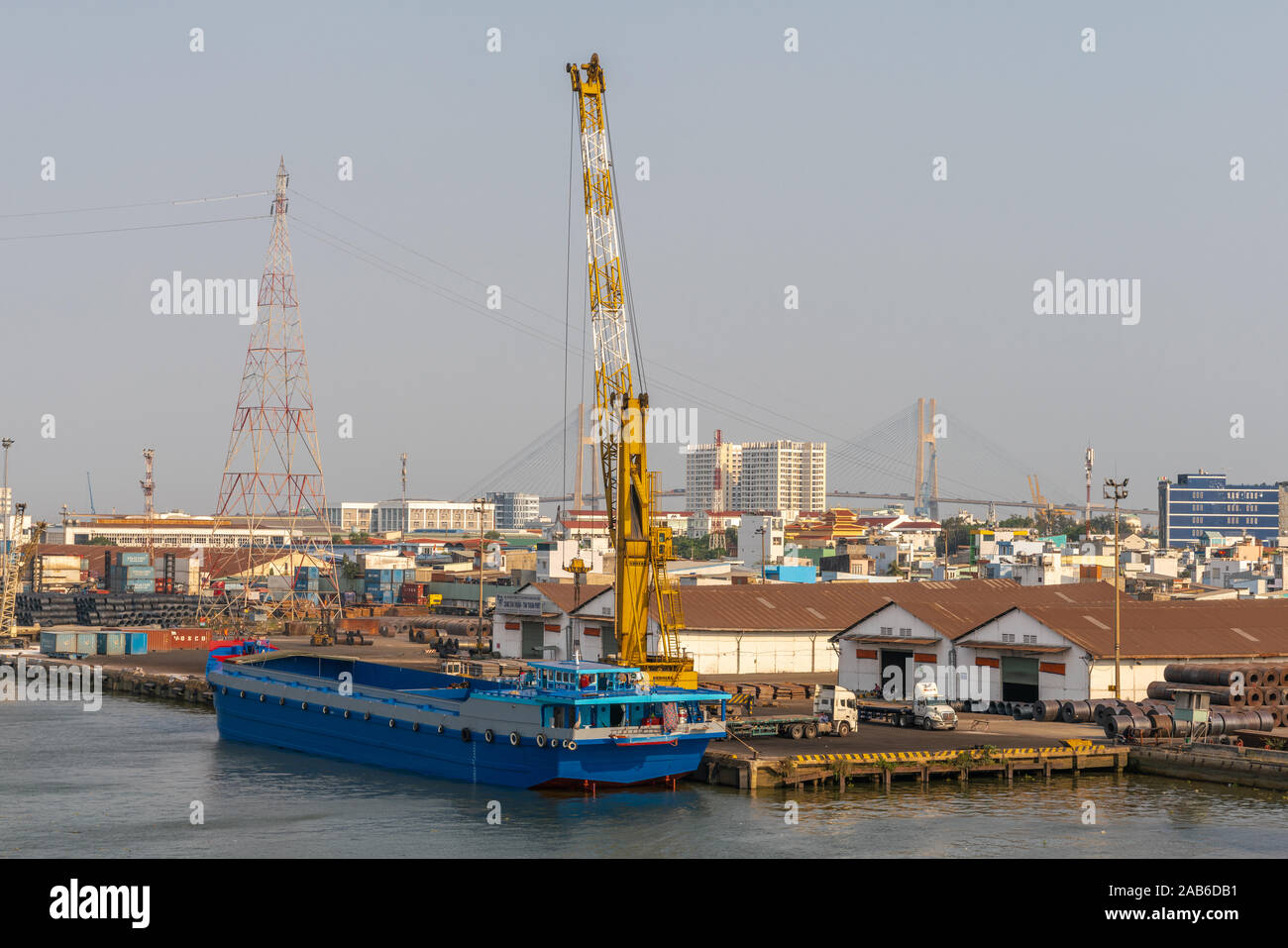 Ho Chi Minh City, Vietnam - March 13, 2019: Tan Thuan port on Song Sai Gon river at sunset. Blue new wide barge with empty flat bed trucks and huge Li Stock Photo