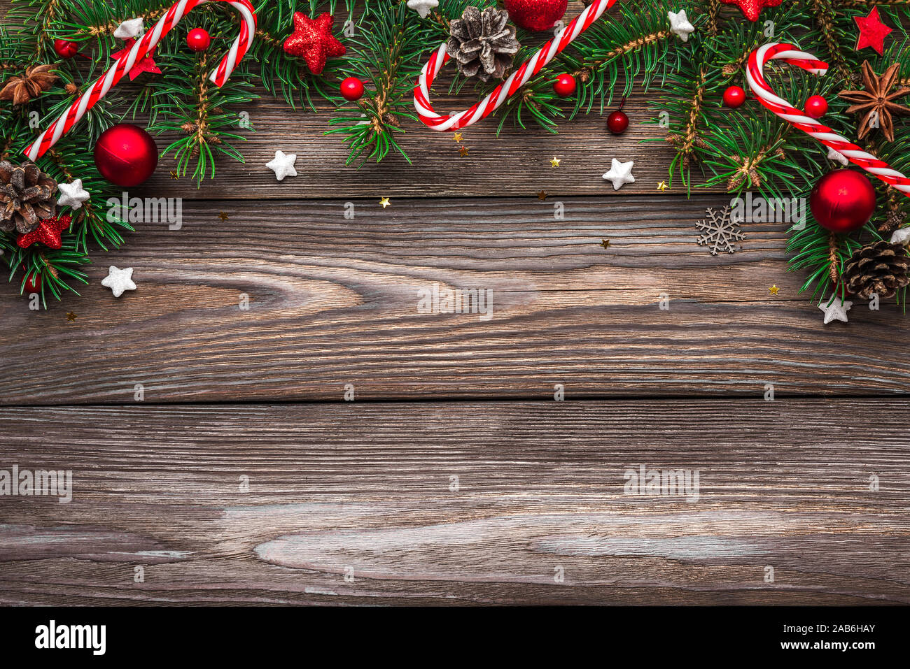 Christmas and Happy New Year composition. Fir tree branches, red holiday decorations and candy on rustic wooden table. top view. flat lay with copy sp Stock Photo