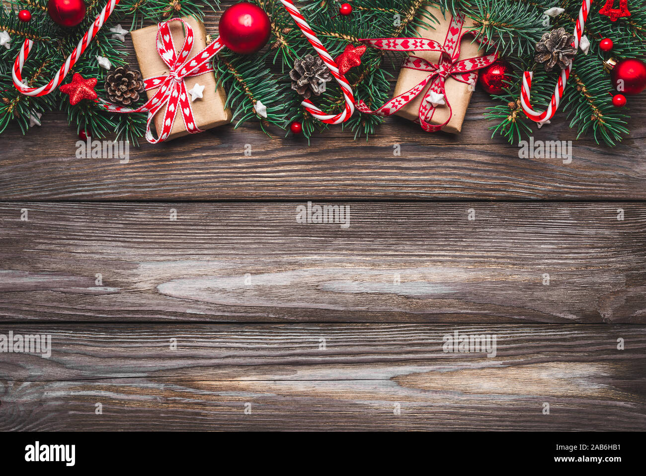 Christmas composition. Fir tree branches, gift boxes, decorations, candy, pine cones on rustic wooden table. Christmas, winter, new year concept. Flat Stock Photo