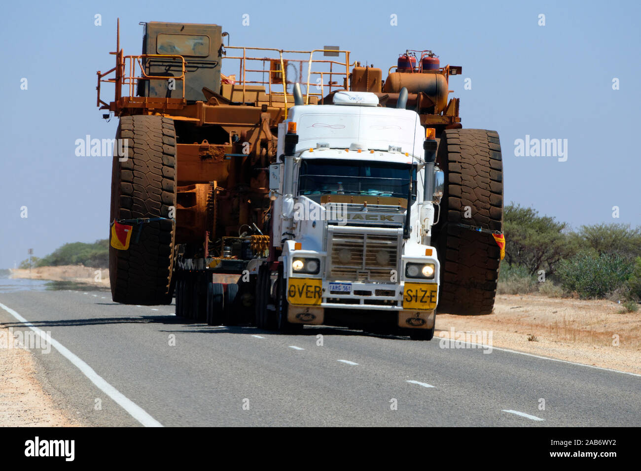 Over size road transport of a Dump truck on a very hot outback highway with heat shimmer, Western Australia Stock Photo